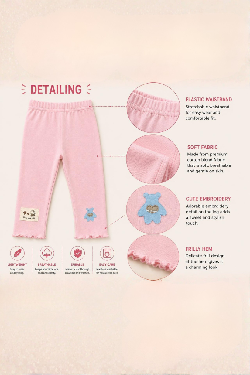 Detailed view of pink baby pants with text on a light pink background