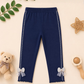 Navy blue leggings with bow details on a beige background with decorative elements.