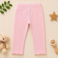 Pink pants on a beige background with a teddy bear and star decorations.