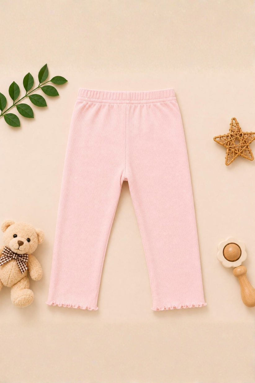 Pink baby pants on a beige background with toys and leaves.